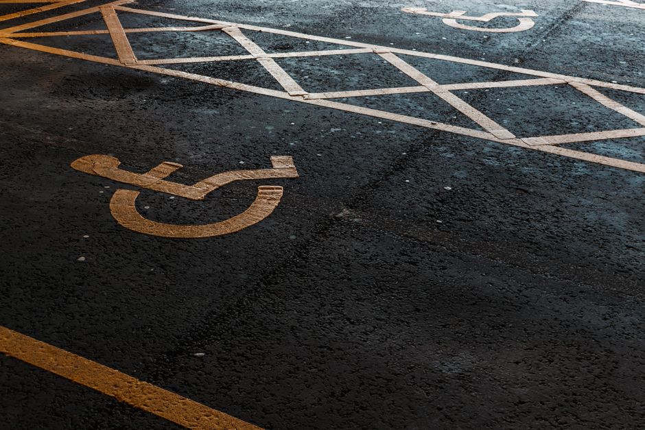 Close-up of an accessible parking symbol on a dark asphalt surface, featuring evening light.