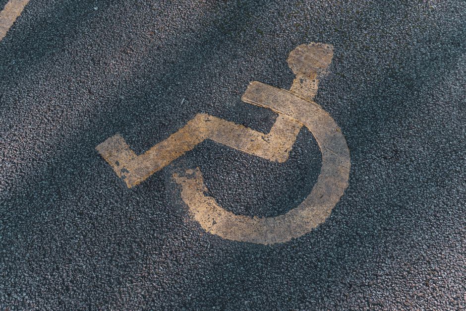 A close-up of a wheelchair symbol on asphalt, representing accessibility.