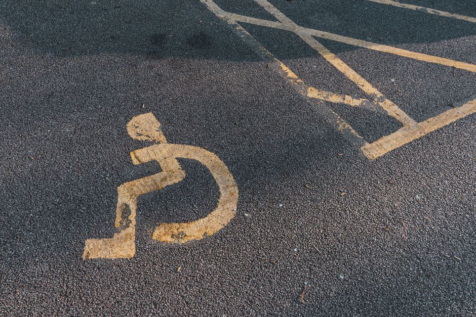 A faded disabled parking symbol painted on asphalt pavement, highlighting accessibility.