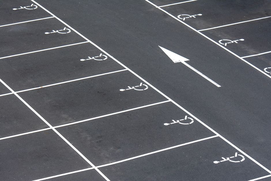An aerial view of an empty parking lot with handicap spaces and directional arrow.
