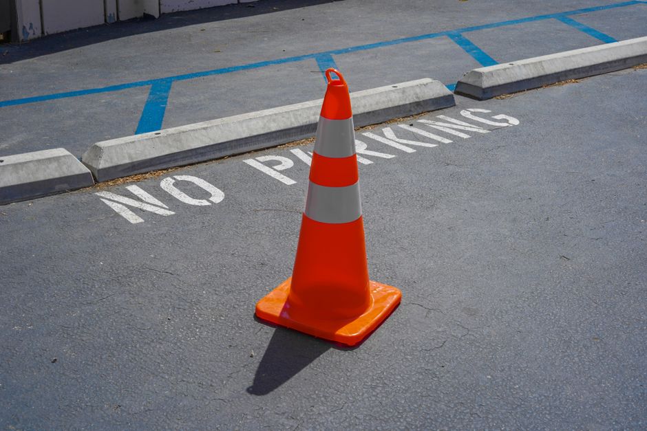 Orange traffic cone placed in a no parking zone on a city street parking lot.